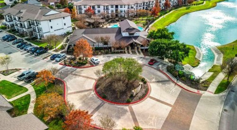 an aerial view of an apartment building and a pond